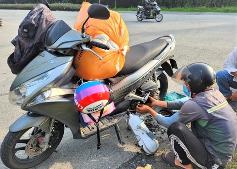 Thợ sửa xe máy lưu động đang vá xe cho khách hàng trên đường phố đông đúc