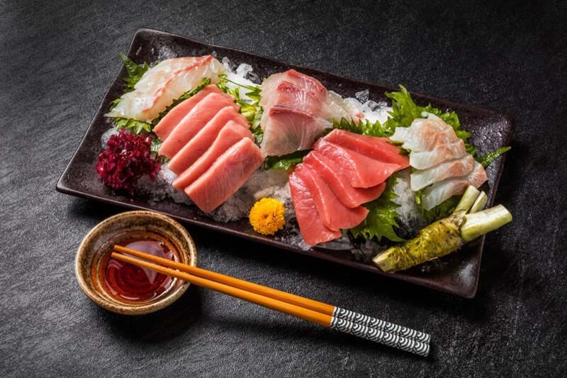 Người đầu bếp kiểm tra độ tươi của miếng cá hồi trước khi chế biến sushi