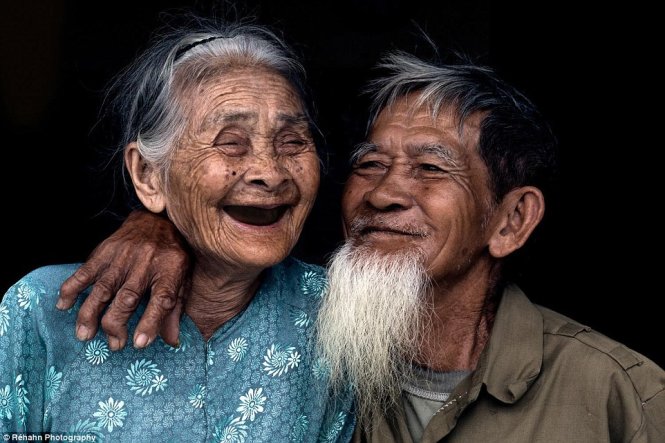 Người phụ nữ lớn tuổi ngắm nhìn bức ảnh gia đình đã phục chế với nụ cười hạnh phúc