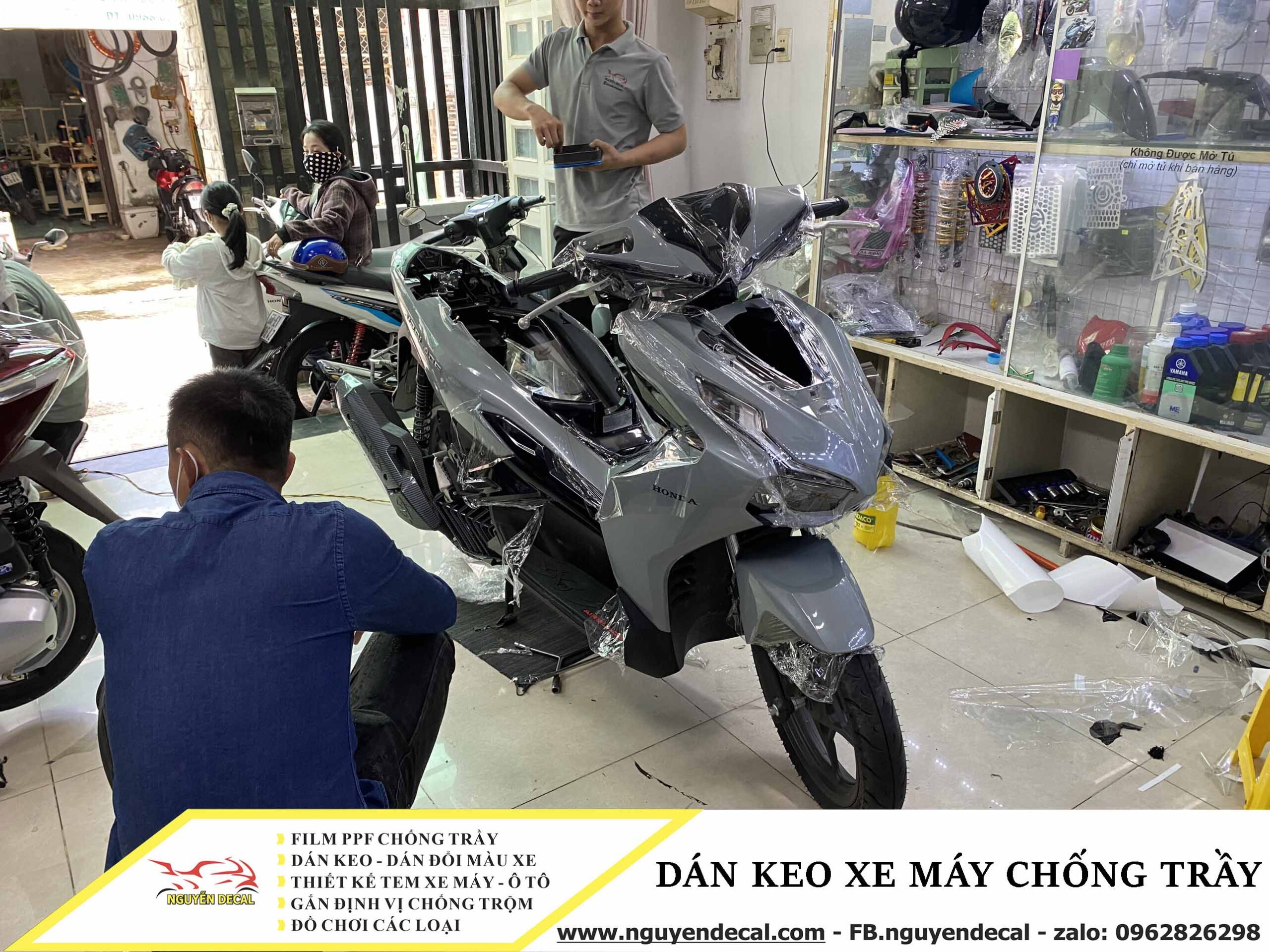 Thợ dán keo xe máy đang tỉ mỉ dán keo bảo vệ cho xe