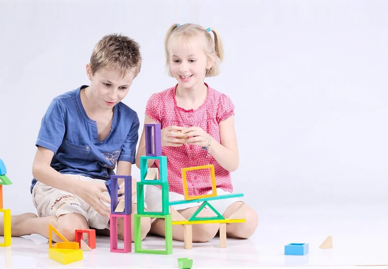 Bé gái đang chơi với bộ đồ chơi gỗ nhiều màu sắc các khối gỗ được bo tròn cẩn thận không có cạnh sắc nhọn