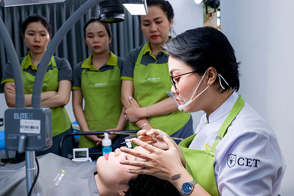 Giảng viên đang hướng dẫn học viên thực hành kỹ thuật phun xăm trên da nhân tạo
