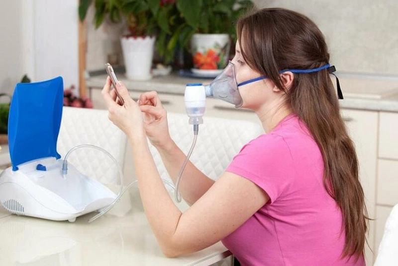 Người lớn tuổi đang sử dụng máy xông khí dung tại nhà có bác sĩ tư vấn bên cạnh